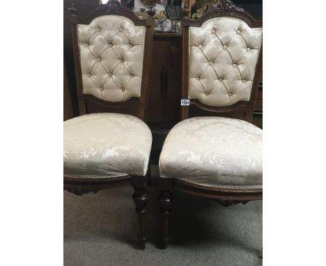 A pair of Edwardian occasional chairs with button back upholstery on turned legs .
