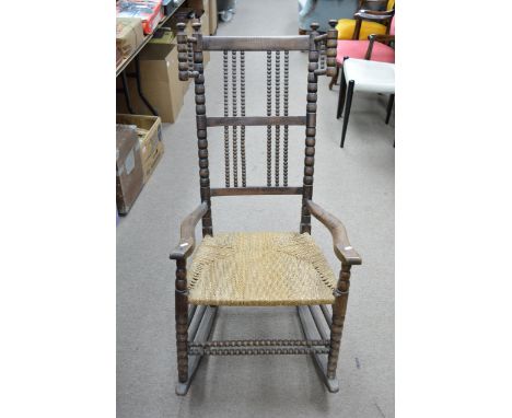 An ash and beech rocking chair designed by Ernest Gimson for Robert Weir Shultz with bobbin turned uprights and wings, turned