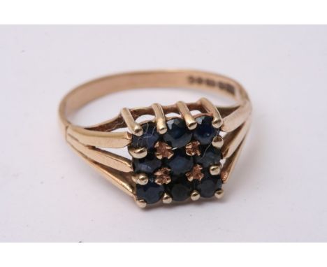 A 9ct gold ring set with a square pattern of blue sapphires,