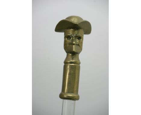 A glass walking stick with a brass handle depicting a figure wearing a hat