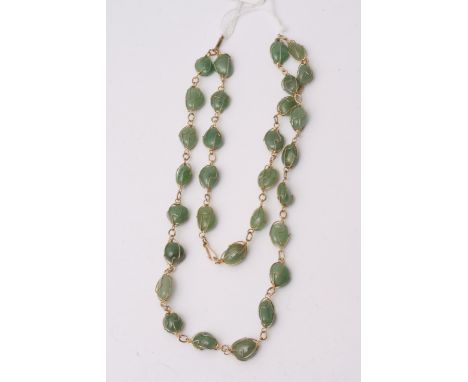 A jade necklace set on gold tone metal, comprising of 30 pieces of jade