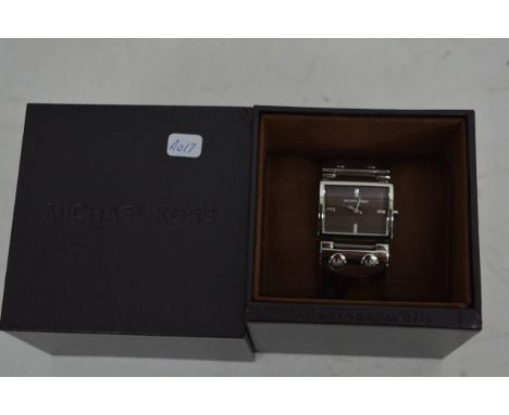 A boxed ladies Michael Kors wristwatch of rectangular shape mounted on a tortoise shell type bangle
