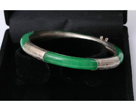 A vibrant green jade bangle held in a 925 silver bangle etched with light detailing in a presentation box