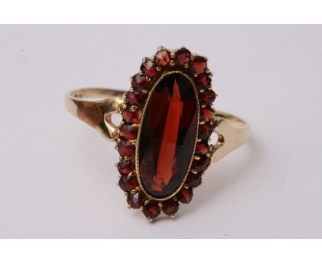 A 9ct gold ring set with an oval almadine garnet and surrounded by smaller examples, approx weight 2.5g and size W.