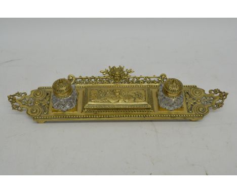 A double brass inkwell decorated with cherubs.