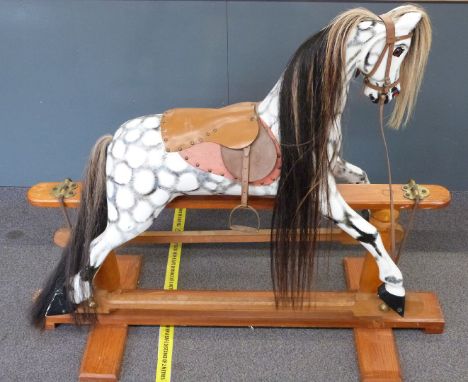 A wooden dapple grey rocking horse with hair mane and tail, leather saddle and reins, metal mounts and wooden base, 160cm lon