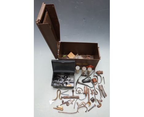 A collection of gun parts and accessories including scope mounts, hammers, trigger guards etc in a vintage military ammunitio