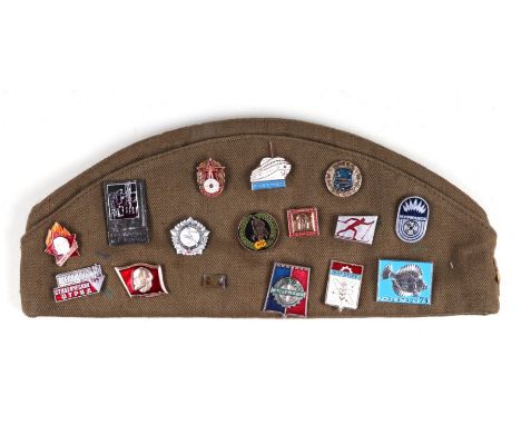 A Russian military side cap with a quantity of Russian enamel badges.