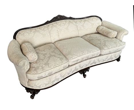 A late Victorian / Edwardian upholstered three-seater sofa with carved show wood and gnarl front feet, 210cms long.