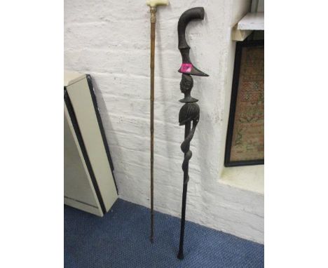 A Victorian bamboo walking stick with a bone handles and an African carved walking cane 