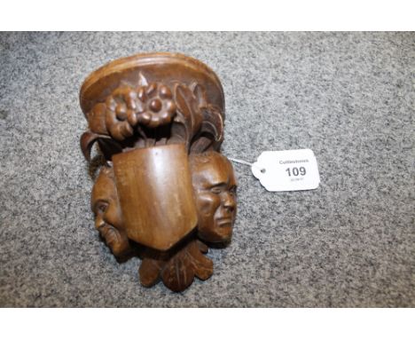 A FRENCH STYLE WALNUT SMALL WALL BRACKET, carved with two heads either side of a shield with flowers above, H 12 cm