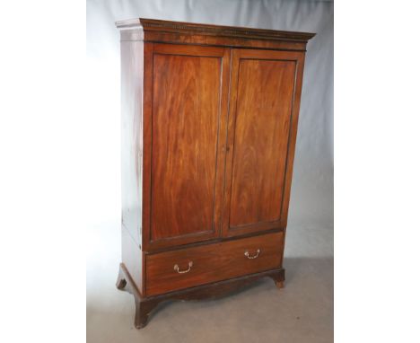 An early 19th century mahogany press cupboard, with dentil moulded cornice over a pair of ebony strung panelled doors and a s