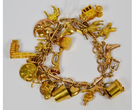 A charm bracelet, alternate links stamped '9' '.375', hung with twenty six charms and one loose, including a cap, a boot, a c