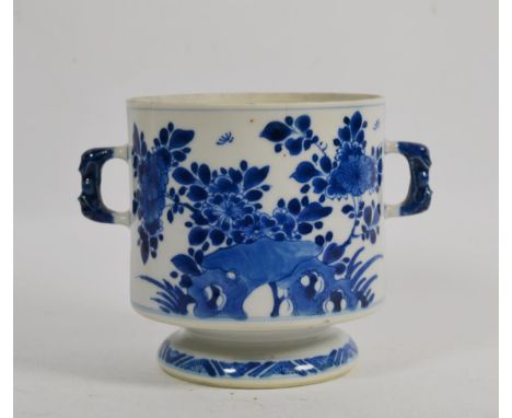 An 18th century Kangxi blue and white porcelain twin handled cup, (lacking cover), decorated with flowers 