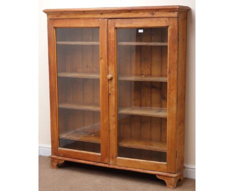 Early 20th century pitch pine bookcase, two glazed doors enclosing four shelves, bracket supports, W133cm, H155cm, D30cm