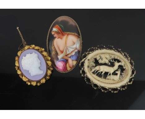 An Italian oval painted porcelain brooch, depicting a lady playing the lute, in a gilt meta frame, a 19th century carved ivor