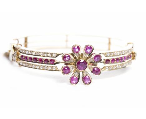 EARLY TWENTIETH CENTURY RUBY AND DIAMOND BANGLEwith a ruby set floral motif proud of the body of the bangle and set with rows