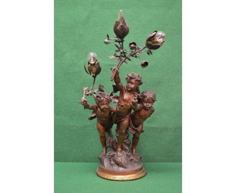 Bronzed spelter cherub table lamp having three cherubs holding flower formed lamp fittings on a circular gilt metal base, sig