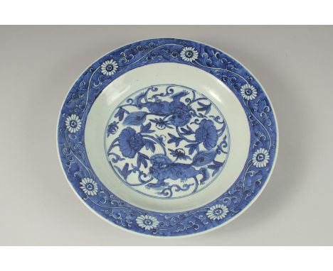 A CHINESE BLUE AND WHITE PORCELAIN CHARGER, painted with central floral panel depicting two lion dogs, 33cm diameter.