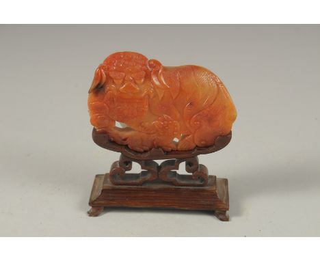 A GOOD CHINESE CARVED JADE DOG OF FO, 9cm long, 6cm wide, on a wooden stand.