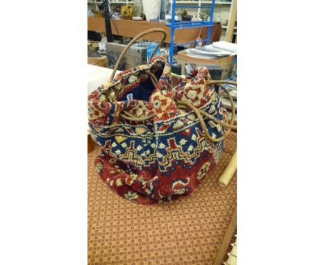 A carpet bag handbag with leather straps.