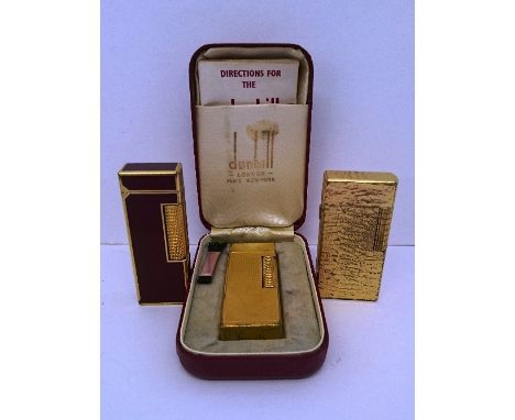 A Dunhill gold plated engine turned cigarette lighter in original presentation case together with two other Dunhill cigarette