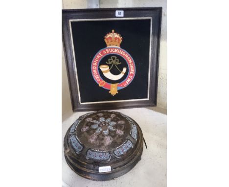 A 19th century circular beadwork foot stool together with a framed woven Military Crest: Oxfordshire and Buckinghamshire Ligh