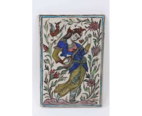 Iznik style tile, decorated with a woman playing a stringed instrument, with foliate patterns in the background, 35cm x 24cmC