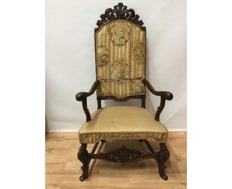 17th century and later oak open arm chair, the high tapestry upholstered back with pierced and carved cresting, scroll carved