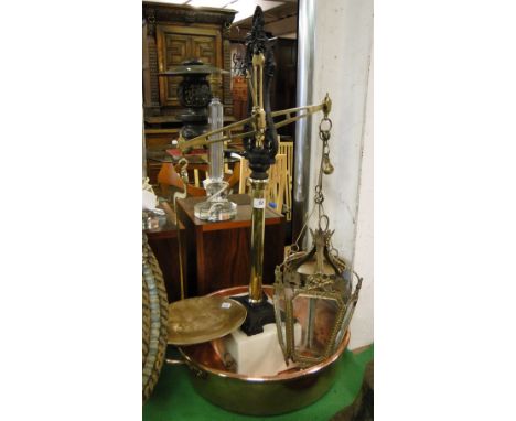 A large brass balance scale, a brass framed lantern and a copper jam pan.