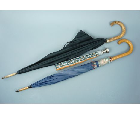 Three vintage umbrellas, two having cane handles, the third of compact design