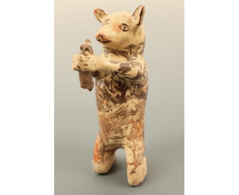 A naive agate glazed terracotta model of a pig holding a rodent, the pig modelled in a kneeling position holding aloft the ra