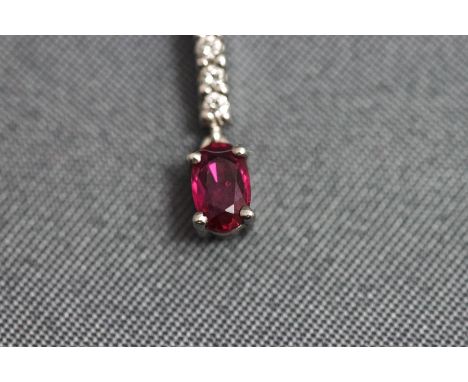 A ruby and diamond pendant, the oval cut to a baton of five small brilliant cuts, on a 9 carat white gold chain, pendant 14 m