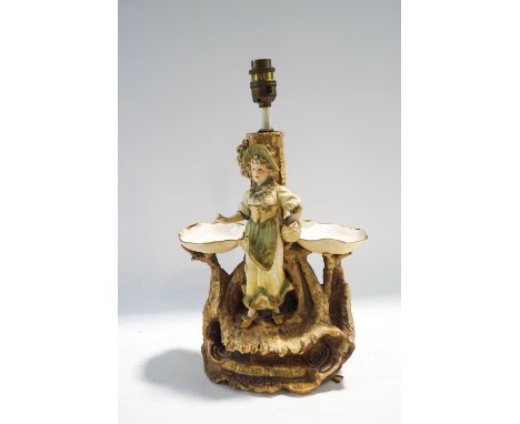 An Austrian ceramic figural table lamp, modelled as a lady in fine clothes upon a naturalistic base, factory marks to undersi