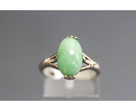A jade ring, the white mount stamped '18K', the oval cabochon, approximately 12mm long by 7.5 mm wide, finger size K1/2, 3.4 