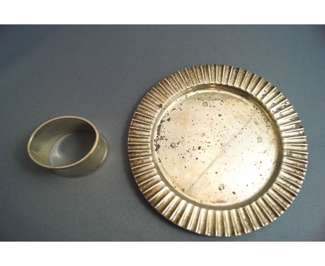 A flat silver dish, Sheffield 1973, 14cm diameter, 112 g (3.6 troy ozs) gross; together with a white metal napkin ring