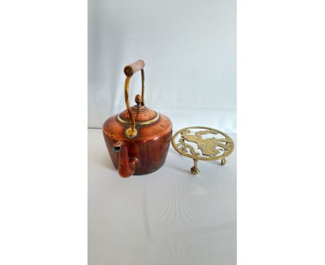 Copper kettle with brass paw-feet stand and wood-clad handle.