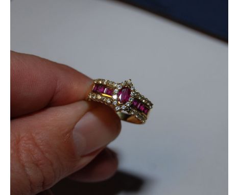 AN 18CT. RUBY AND DIAMOND RING, THE CENTRAL RUBY FLANKED BY SIX SQUARE STONES AND SMALL DIAMONDS IN THE OUTER RING
