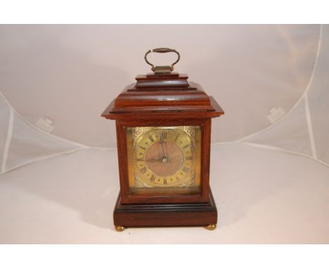 MAHOGANY MANTEL CLOCK WITH BELL TOP CASE AND BRASS CARRY HANDLE. BEVELLED GLASS TO FRONT, BRASS DIAL WITH CORNER SPANDRELS, R