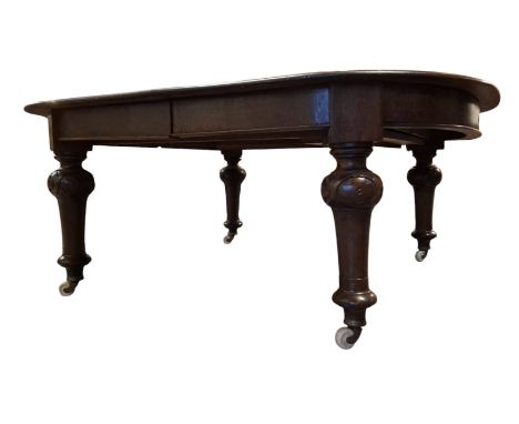 A large 19th century mahogany extending dining table. The table having a rectangular top with curved chamfered edges. Fitted 