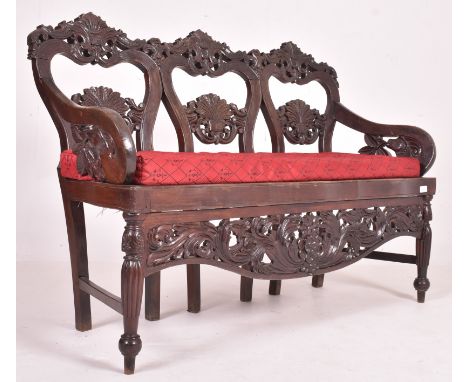 An Indo - Portuguese manner hardwood hall bench settle. The bench having a carved pierced back rest with scrolled foliate mot