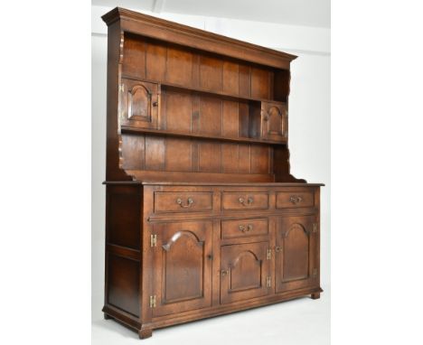 A George III Revival Ipswich solid oak Welsh dresser. The dresser having a flared pediment top with plate shelf over two smal