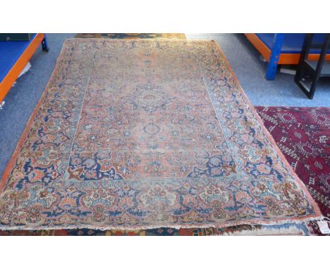 A late 19th century North-West Persian&nbsp;Sarouk carpet: central blue teardrop medallion against a red field. (Worn conditi