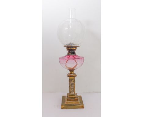 A 19th century glass and brass oil lamp: foliate style decorated spherical glass shade and cranberry glass style reservoir be