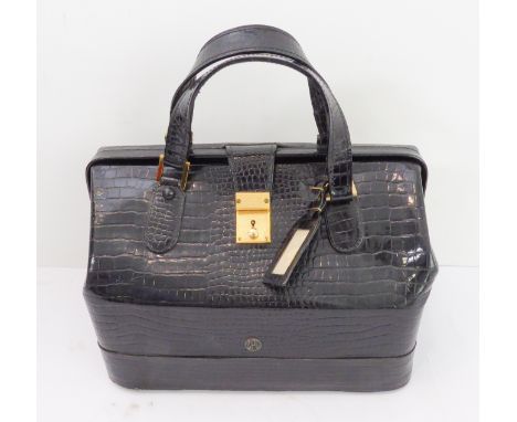 A black crocodile leather vanity case by Asprey of London: gold toned fittings, two top handles, the scissor-hinged top openi