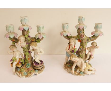A pair of late 19th century German porcelain three-light figural candelabra: 1. a boy treading grapes, another raising a cup 
