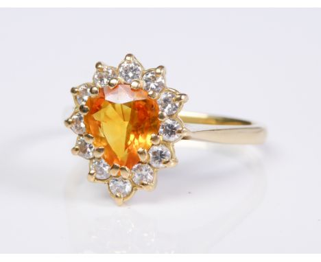 A yellow sapphire and diamond-set cluster ring, the pear-shaped yellow sapphire within a surround of twelve brilliant-cut dia