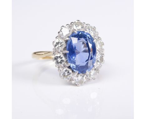 A sapphire and diamond-set cluster ring, the oval mixed-cut sapphire (10.5mm x 7.7mm x 5.4mm) within a border of ten brillian