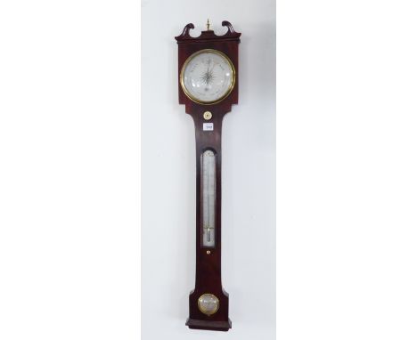 An early 19th century mahogany wheel barometer: the broken swan-neck pediment surmounted with a small gilt-metal urn-style fi