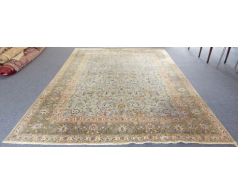 A large Persian Tabriz carpet: light green ground with stylised floral and foliate designs within mustard and dark green bord